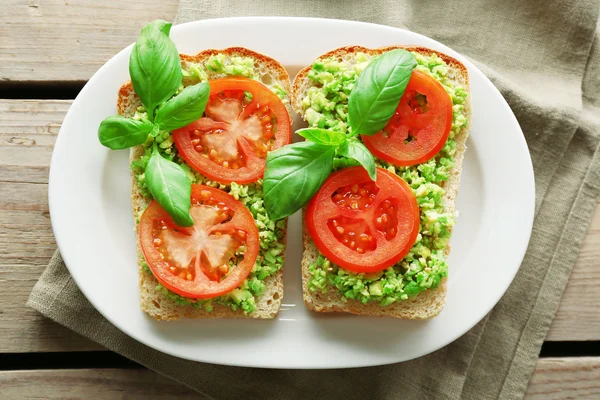 Sandwich vegano con aguacate y verduras en plato, sobre fondo de madera —  Fotos de Stock