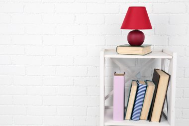 Kitap ve tuğla duvar arka lamba ile ahşap raf