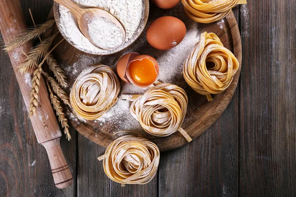 Rohe hausgemachte Pasta und Zutaten für Pasta auf Holzgrund — Stockfoto