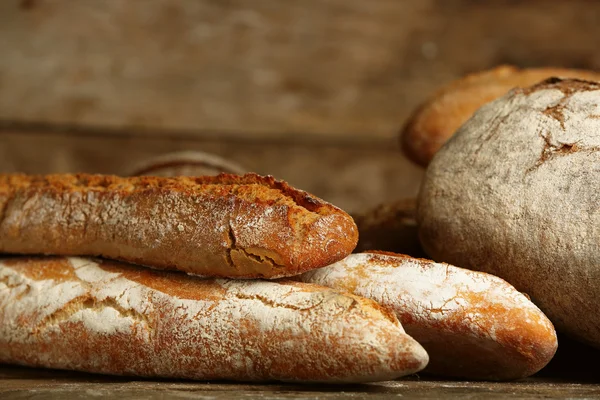 Different fresh bread on old wooden table — Stock Photo, Image