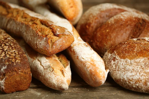 Eski ahşap masa üzerinde farklı taze ekmek — Stok fotoğraf