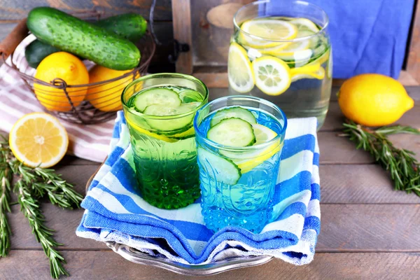 Fresh water with lemon and cucumber in glassware with napkin on wooden background — Stock Photo, Image