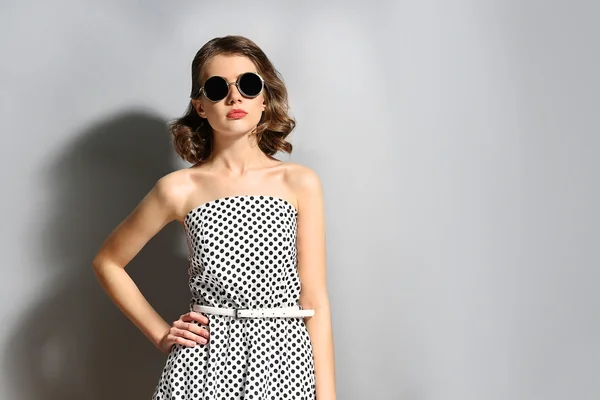 Porträt des schönen Modells im Punktekleid mit Sonnenbrille auf grauem Hintergrund — Stockfoto