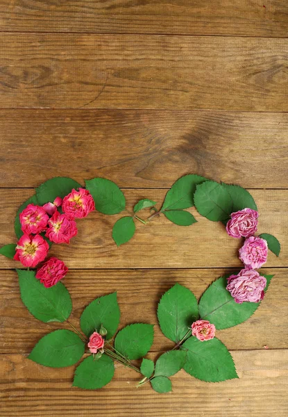 Herz aus schönen trockenen Blumen und grünen Blättern auf Holzgrund — Stockfoto