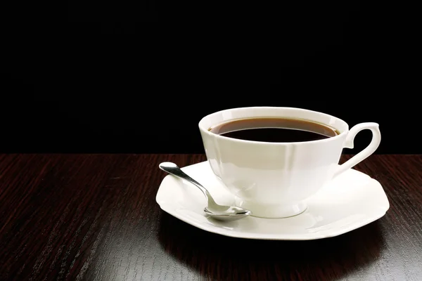 Tasse Kaffee auf Holztisch, auf dunklem Hintergrund — Stockfoto