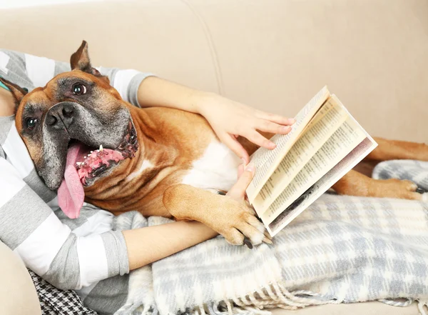 Lindo perro y chica tumbado en el sofá, en el fondo interior del hogar — Foto de Stock