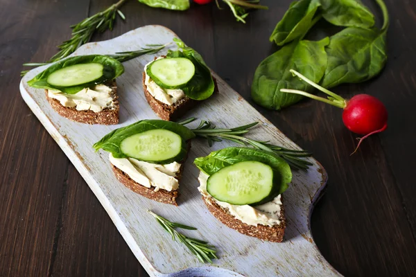 Deliciosos sándwiches con verduras y verduras en la tabla de cortar de cerca —  Fotos de Stock