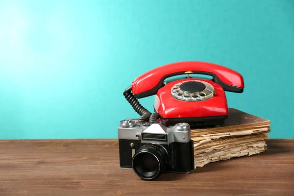 Retro camera with old book and telephone on table on green background — Stock Photo, Image
