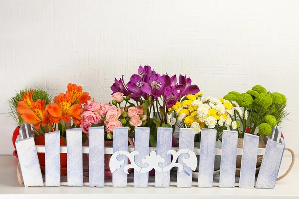 Όμορφα λουλούδια στην δεξιοτεχνίας γλάστρα επάνω ελαφρύς υπόβαθρο — Φωτογραφία Αρχείου