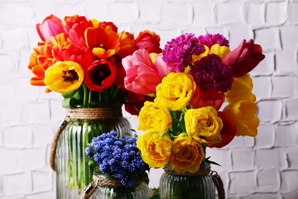 Beautiful flowers in vases on wall background — Stock Photo, Image