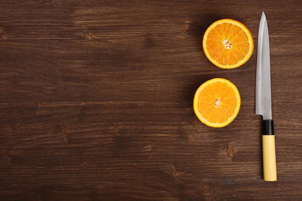 Mitades de naranja con cuchillo sobre fondo de madera —  Fotos de Stock