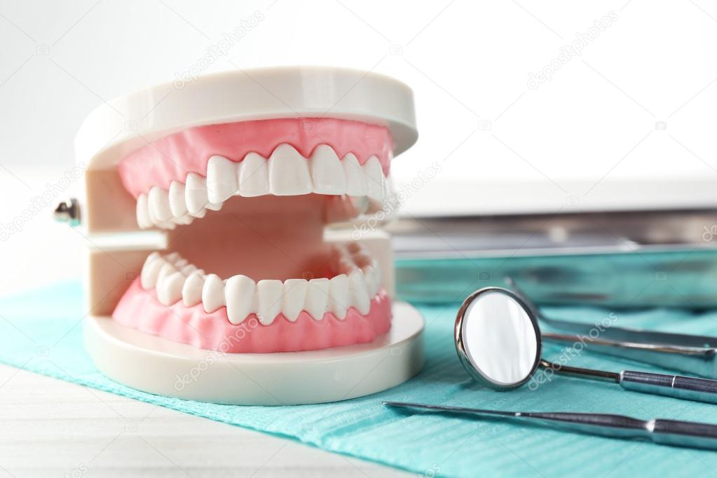 White teeth and dental instruments on table background