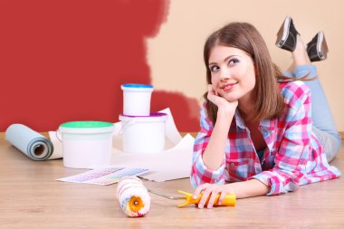 Güzel kız boyama duvar için ekipman ile yerde yatarken