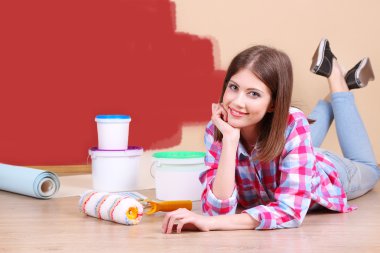 Güzel kız boyama duvar için ekipman ile yerde yatarken