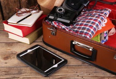 Packing suitcase for trip on wooden background