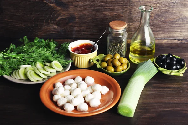 Queso mozzarella con aceitunas y verduras sobre fondo de madera —  Fotos de Stock