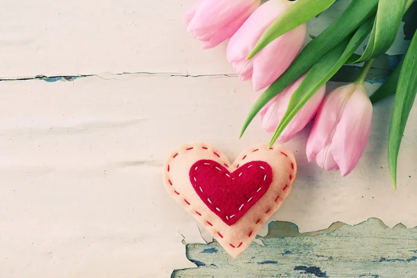 Bei tulipani rosa con cuore decorativo su sfondo di legno — Foto Stock