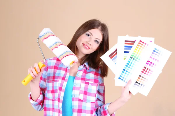 Menina bonita com rolo e paleta de cores perto da parede — Fotografia de Stock