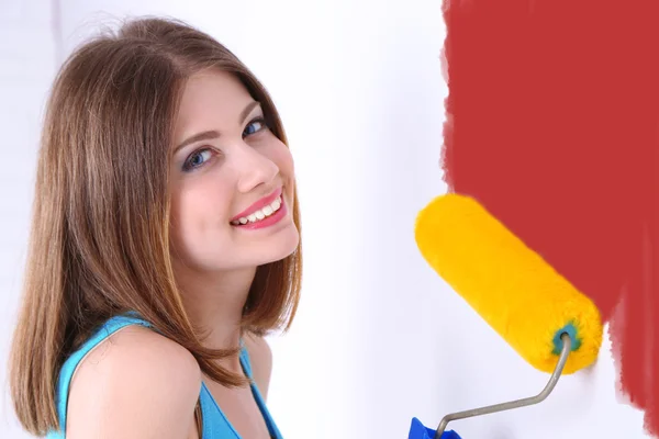 Beautiful girl paints wall in room — Stock Photo, Image