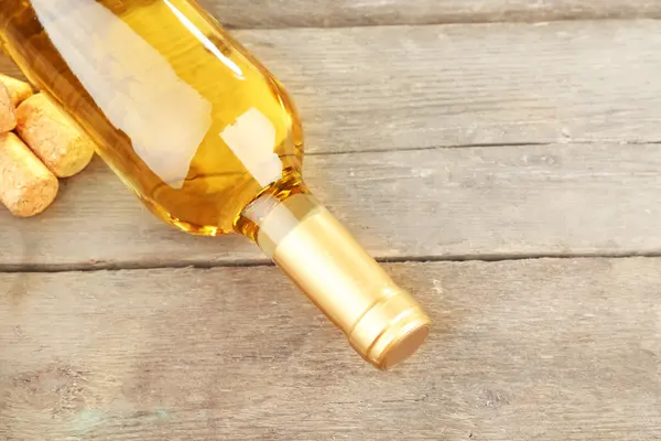 Glass bottle of wine with corks on wooden table background — Stock Photo, Image