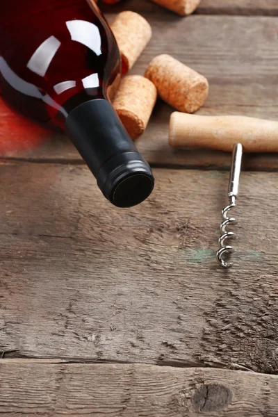 Garrafa de vidro de vinho com rolhas e saca-rolhas sobre fundo de mesa de madeira — Fotografia de Stock