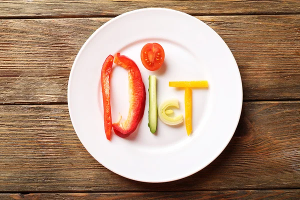 Word DIET en tranches de légumes dans une assiette blanche sur une table en bois, vue de dessus — Photo