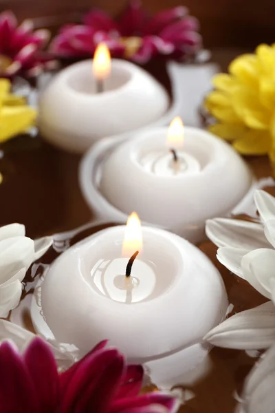 Kom met spa water met bloemen en kaarsen, close-up — Stockfoto
