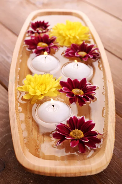 Tigela de água termal com flores e velas em mesa de madeira, close-up — Fotografia de Stock