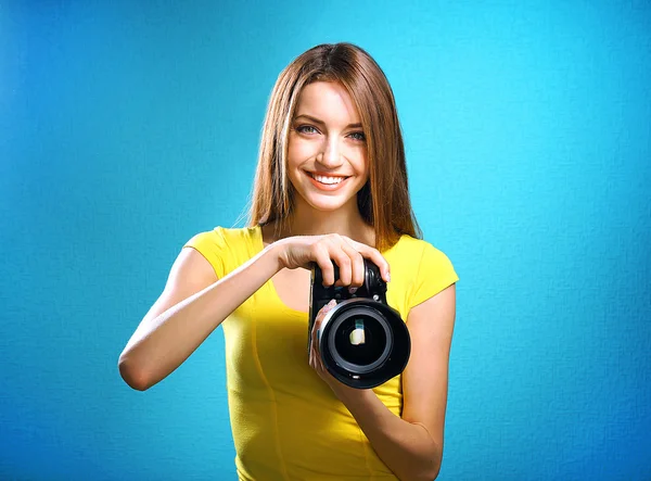 Jovem fotógrafa tirar fotos no fundo azul — Fotografia de Stock