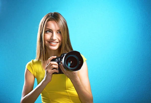 Joven fotógrafa tomando fotos sobre fondo azul — Foto de Stock