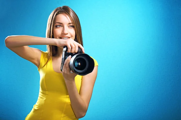 Joven fotógrafa tomando fotos sobre fondo azul — Foto de Stock