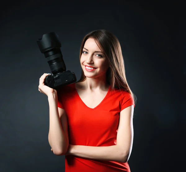 Young female photographer taking photos on black background — Stock Photo, Image