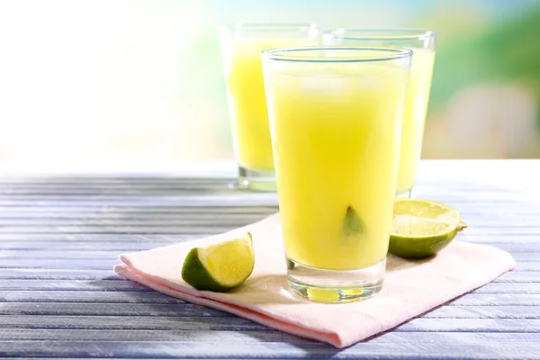 Glasses of cocktails on wooden table on bright blurred background — Stock Photo, Image