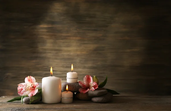 Beautiful composition with candles and spa stones on wooden background — Stock Photo, Image