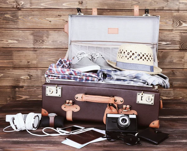 Упакованный чемодан с вещами для отдыха на деревянном фоне — стоковое фото