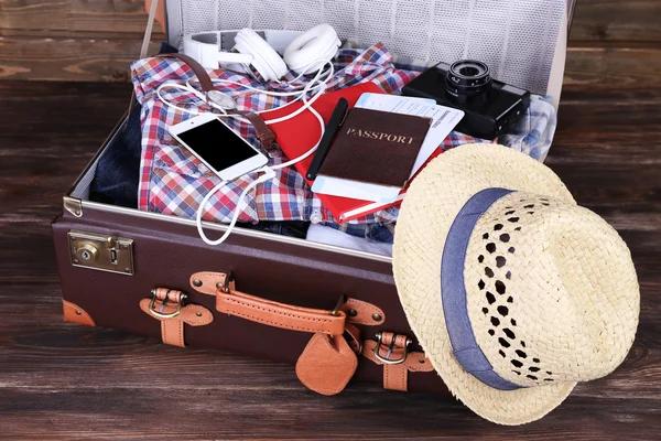 Mala embalada de itens de férias em fundo de madeira — Fotografia de Stock