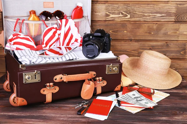 Gepackter Koffer mit Urlaubsartikeln auf Holzgrund — Stockfoto