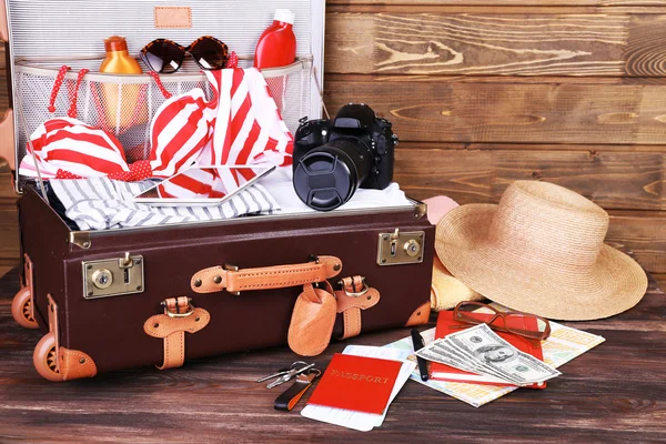 Packed suitcase of vacation items on wooden background — Stock Photo, Image