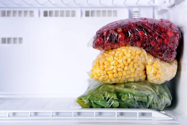 Frozen berries and vegetables in bags in freezer close up — Stock Photo, Image