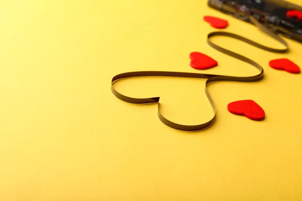 Cassete de áudio com fita magnética em forma de coração sobre fundo amarelo — Fotografia de Stock