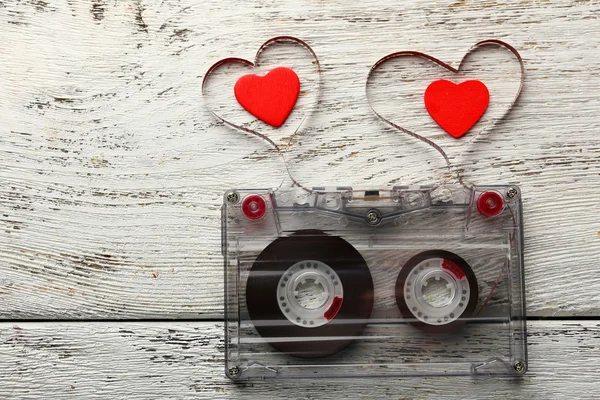 Audio cassette with magnetic tape in shape of hearts on wooden background — Stock Photo, Image