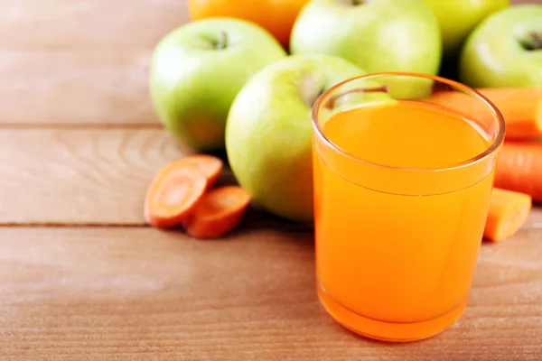 Glas av friska färsk juice av äpplen och morötter på trä bakgrund — Stockfoto