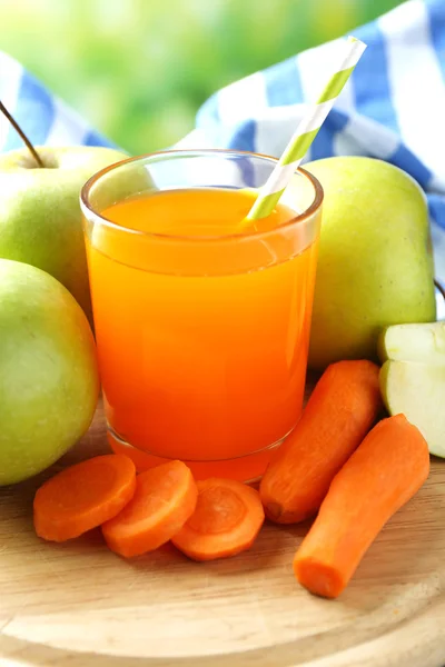 Glass of healthy fresh juice of apples and carrots on wooden table, on bright background
