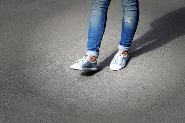 Piedi femminili su sfondo grigio asfalto — Foto Stock