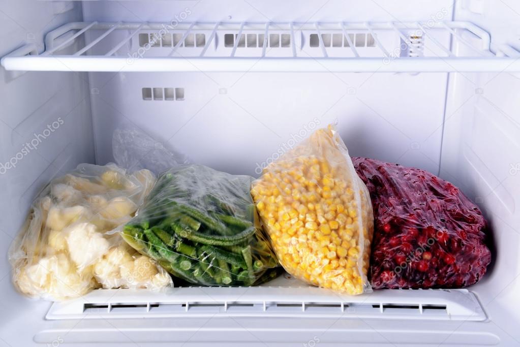 Frozen berries and vegetables in bags in freezer close up