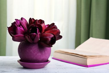 Kumaş arka plan üzerinde kitap ile tencerede güzel Lale