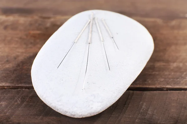 Agulhas de acupuntura em mesa de madeira com pedras de spa, close-up — Fotografia de Stock