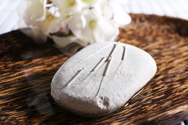 Agujas de acupuntura en placa de madera con piedra de spa, primer plano —  Fotos de Stock