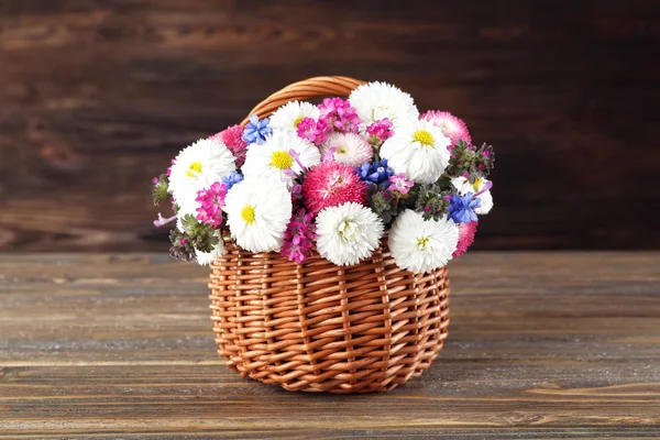 Beautiful colorful daisy in wicker basket on wooden background — Stock Photo, Image