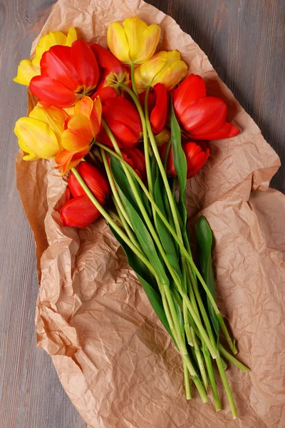 Schöne bunte Tulpen auf Pergament auf Holztisch, Nahaufnahme — Stockfoto
